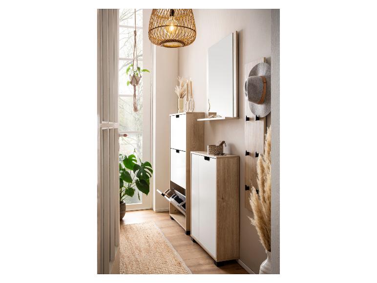 Meubles d'entrée en bois et blanc avec meuble à chaussures, miroir, patère et suspension en rotin.