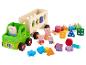 Un camion jouet vert avec des figurines Peppa Pig et des blocs de couleur.