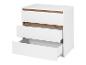 Une commode blanche avec trois tiroirs, dont un est ouvert.