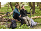 Couple en tenue de randonnée assis sur un tronc d'arbre avec sacs à dos et bâtons de trekking.