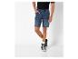 Un homme portant un short en jean bleu foncé et des baskets noires.