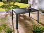 Une table de jardin en métal noir avec un plateau en verre.