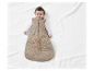 Bébé souriant dans une gigoteuse beige côtelée.