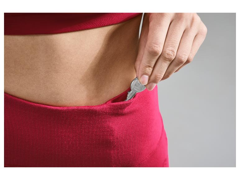 Une main met une clé dans la poche d'un pantalon rose.