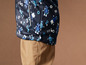 Une veste bleu foncé avec un motif de robots et un pantalon marron.