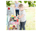 Enfant jouant avec un barbecue jouet dans un jardin.