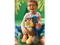 Garçon souriant avec des lunettes et un chien en peluche sur fond vert.