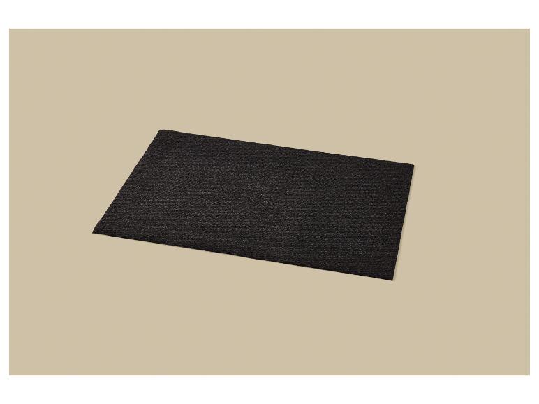 Paillasson noir texturé posé en diagonale sur un fond beige.
