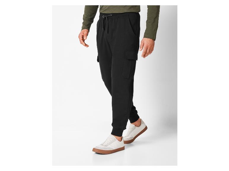 Un homme portant un pantalon cargo noir et des baskets blanches.
