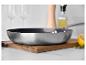 Poêle en acier inoxydable sur planche en bois, accessoires de cuisine.