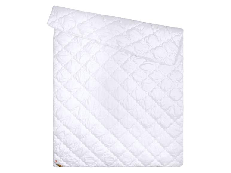 Couette blanche matelassée avec motif, pliée sur fond blanc.