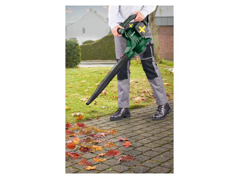 Personne utilisant un souffleur de feuilles pour dégager les feuilles d'automne d'un chemin pavé.