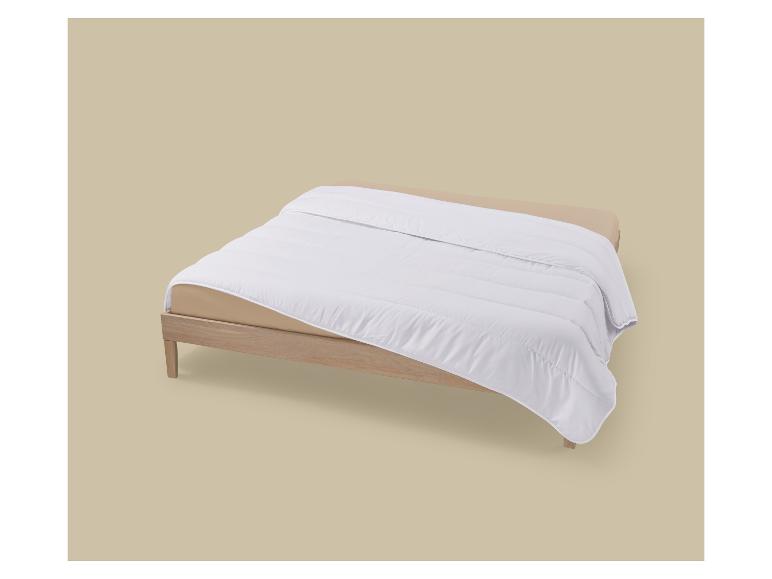Couette blanche sur un cadre de lit en bois clair