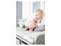 Bébé assis sur une table à langer avec des peluches, une rose et une bleue.