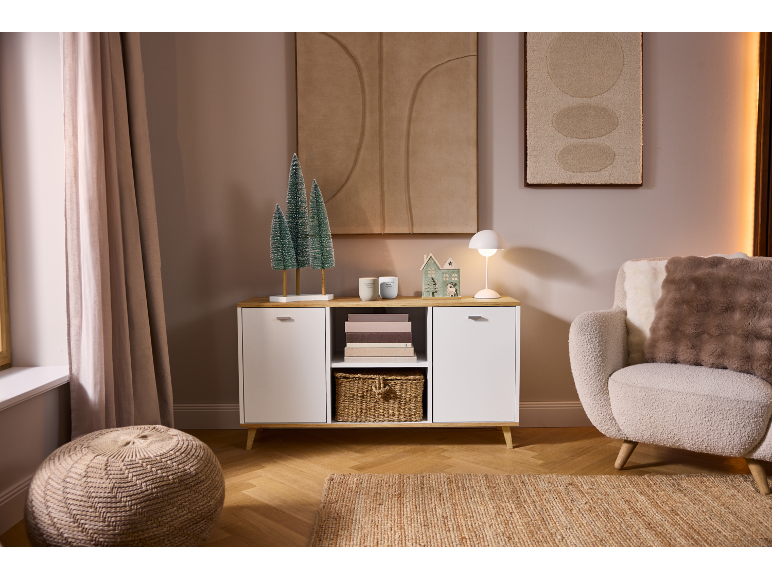 Salon chaleureux avec un buffet blanc, un fauteuil et des décorations de fête.