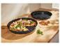 Pizza sur une plaque à pizza noire De Buyer sur une table en bois.