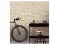 Un vélo et un bureau en bois foncé avec un tabouret contre un mur de briques claires.