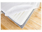 Un matelas blanc avec une housse grise, visible sur un plancher en bois.