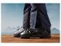 Des chaussures de ski noires sur un sol en bois avec vue sur les montagnes.