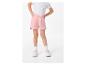 Un enfant portant un short rose, un t-shirt blanc et des baskets blanches.