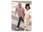 Un homme et une femme marchent dans la rue, il porte un t-shirt rose et elle un pull blanc.