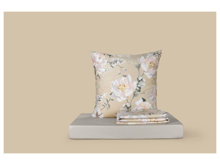 Oreiller à motifs floraux et parure de lit pliée sur une surface gris clair.