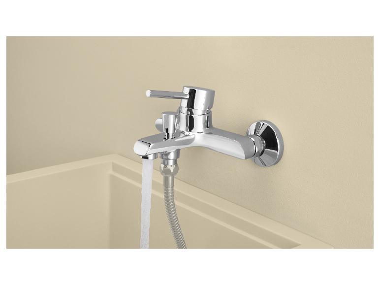 Mitigeur de baignoire chromé avec de l'eau coulant dans une baignoire claire.