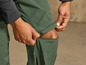 Un homme relève les jambes d'un pantalon de randonnée vert