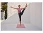 Femme faisant du yoga en extérieur, portant un débardeur lilas et un legging capri noir, sur un tapis de yoga rose.