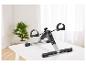Mini vélo d'appartement avec écran numérique sur une table blanche, avec une plante en arrière-plan.