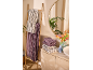 Serviettes rayées sur une échelle en bambou et un meuble de salle de bain, miroir et fleurs.