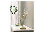 Une lampe en forme d'arbre dorée avec des lumières blanches sur une table blanche.