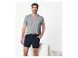 Homme souriant en t-shirt gris et short bleu foncé.