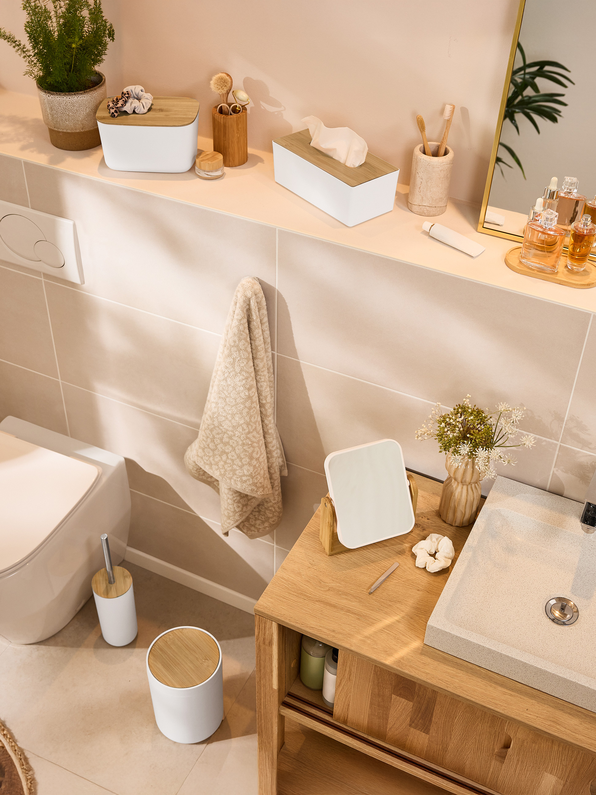 Salle de bain avec accessoires en bambou, toilettes et lavabo.