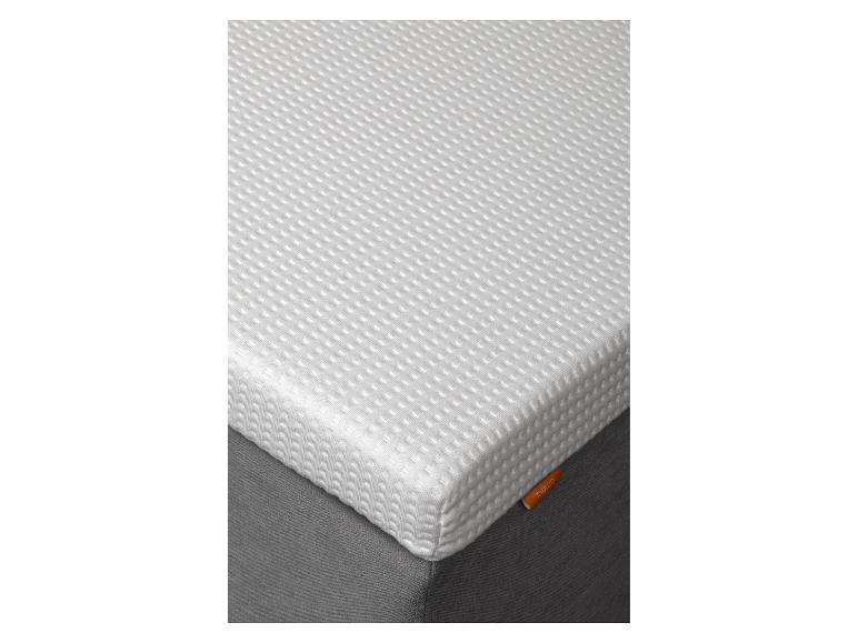Matelas blanc à surface texturée sur une base gris foncé.