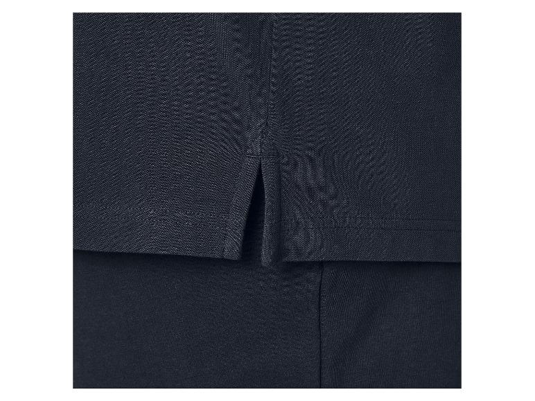 Détail d'un polo bleu marine avec des fentes latérales.