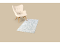 Fauteuil beige avec tapis bleu clair sur fond beige.
