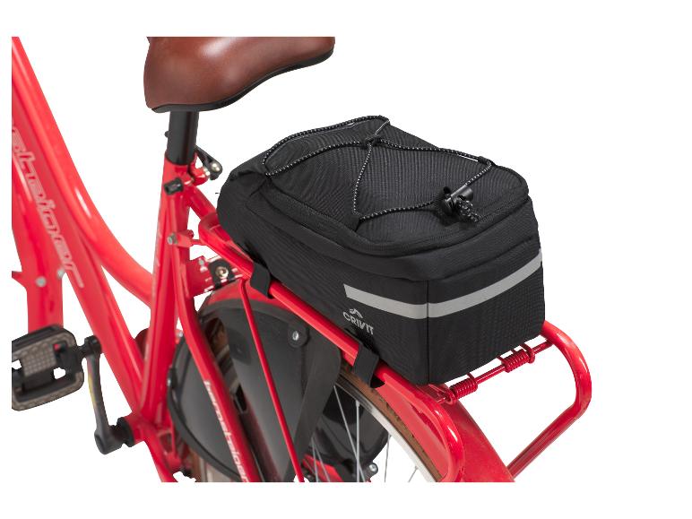 Un vélo rouge avec une sacoche de vélo noire Crivit sur le porte-bagages.