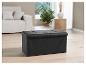 Un coffre de rangement noir avec un siège capitonné dans un intérieur moderne.