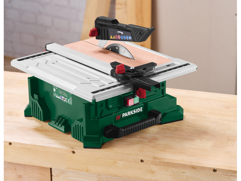 Une scie de table verte et blanche avec une lame circulaire sur un établi en bois.