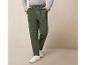 Un homme porte un pantalon cargo vert avec des baskets blanches.