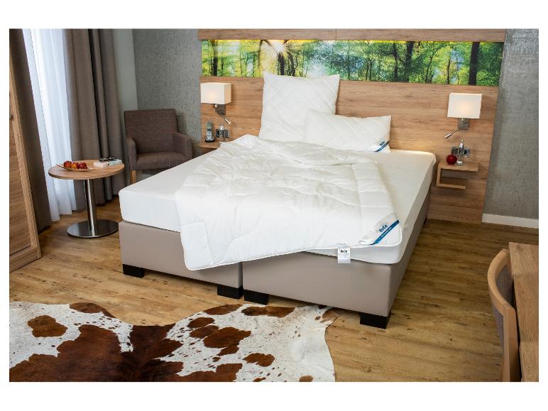 Chambre moderne avec un lit BeCo, décorée d'un tapis en peau de vache et d'un mur sur le thème de la forêt.