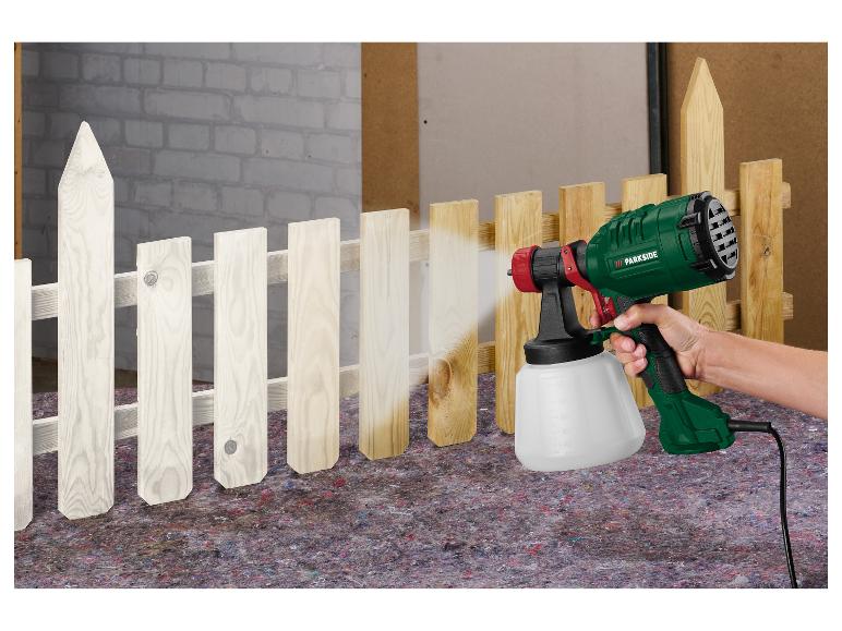 Personne peignant une clôture en bois en blanc avec un pistolet à peinture Parkside.
