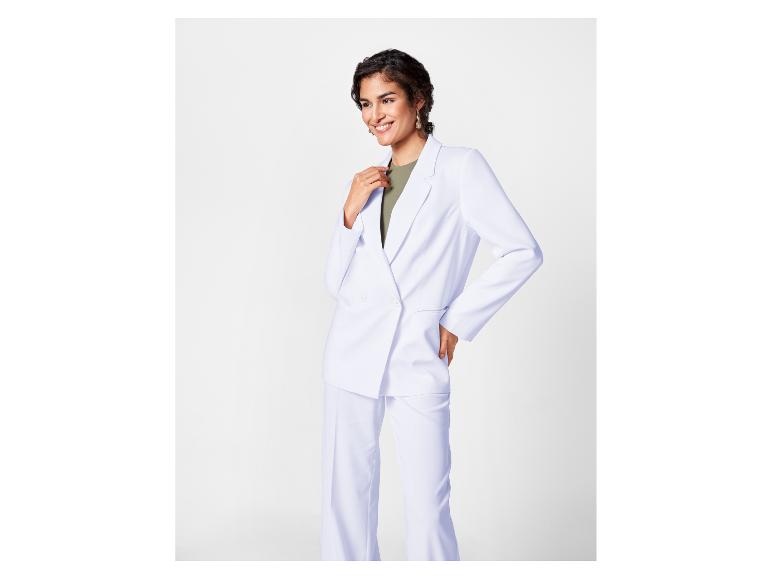 Femme portant un tailleur-pantalon blanc élégant.