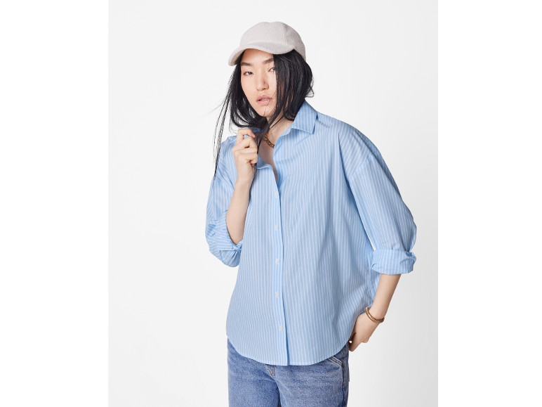 Femme en chemise rayée bleu clair, jean et casquette beige.