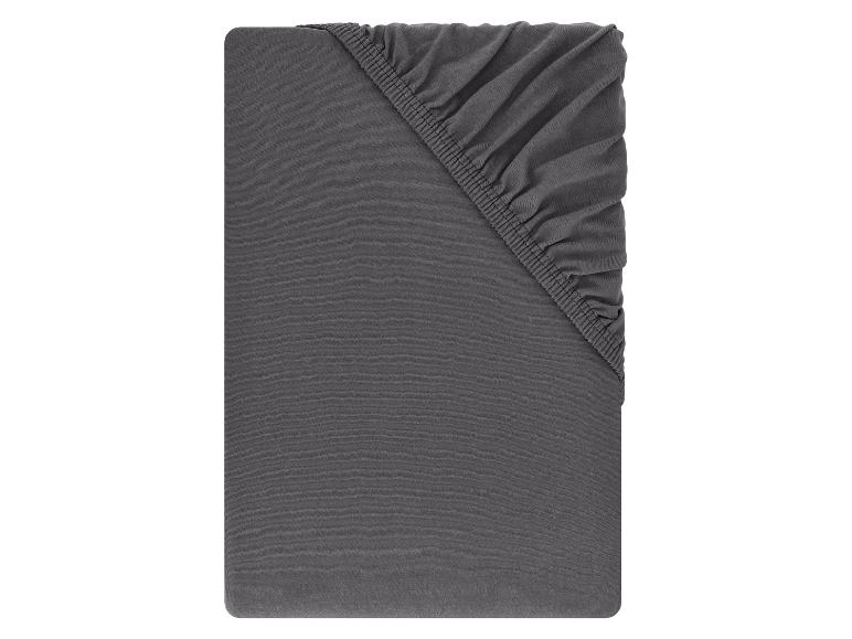 Drap-housse gris foncé plié avec élastique visible dans un coin.