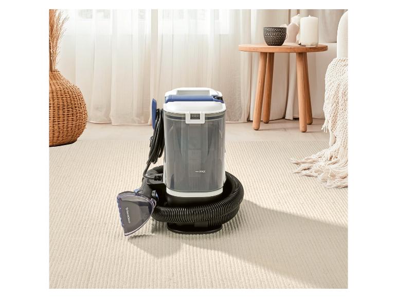 Nettoyeur de tapis et de tissus d'ameublement dans un salon à la décoration neutre.