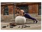 Une femme en chaussures de sport CRIVIT et tenue de sport fait la planche sur un ballon.