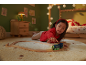 Enfant jouant avec un train en bois sur un tapis dans une chambre douillette.