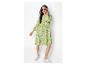 Femme en robe imprimé zèbre vert et blanc, lunettes de soleil et baskets blanches.
